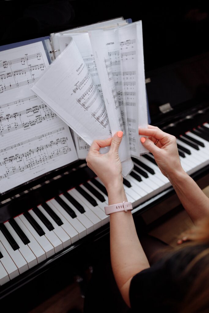 A pianist at a piano flipping through pages of sheet music.