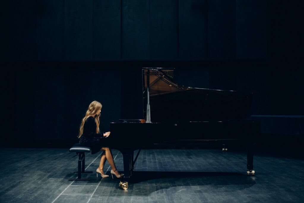 A concert pianist playing a grand piano on a stage.